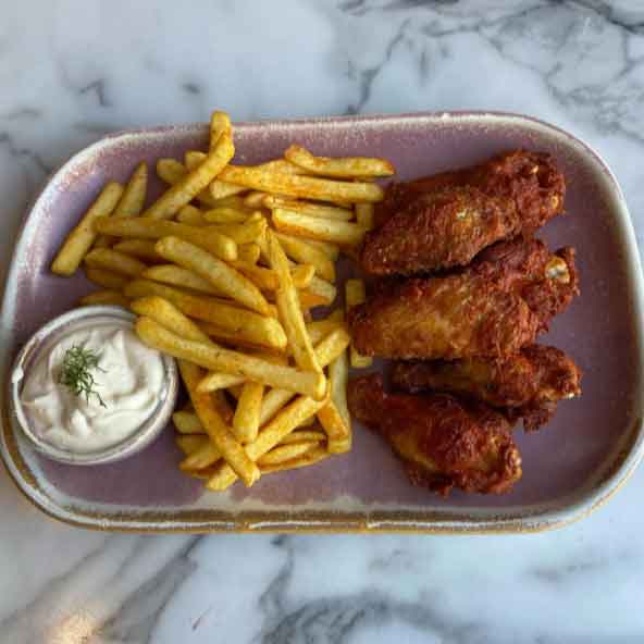 Ada’s fried chicken wings, a pile of French fries and a small dipping sauce.